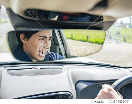 事故を起こしそうな男性ドライバーのルームミラー越しの表情 事故を起こしそうな男性ドライバーのルームミラー越しの表情 119468107