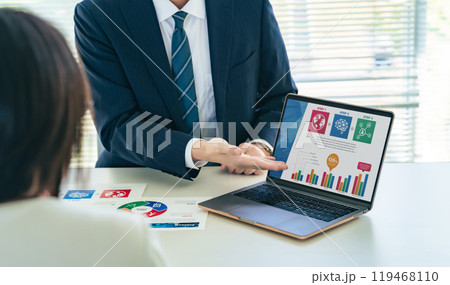 オフィスでノートパソコンの画面を見ながら商談するビジネスパーソンのグループ 119468110