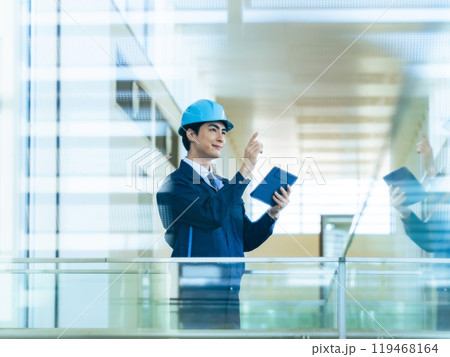 建物の中でタブレットPCを使って点検する男性作業員 建物の中でタブレットPCを使って点検する男性作業員 119468164