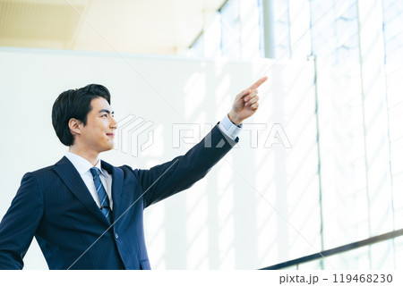 オフィスのロビーで遠くを指さす男性ビジネスパーソン オフィスのロビーで遠くを指さす男性ビジネスパーソン 119468230