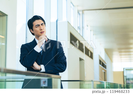 オフィスビルのロビーで考え込む男性ビジネスパーソン 119468233
