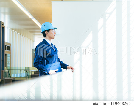 建物の中でタブレットPCを持って遠くを見る男性作業員 建物の中でタブレットPCを持って遠くを見る男性作業員 119468260