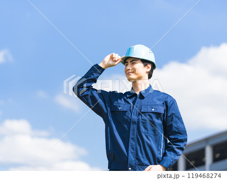 青空の下で工場のような建物の前に立つ作業員 119468274