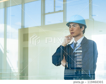 建物の中でガラス越しに考える男性作業員 119468301