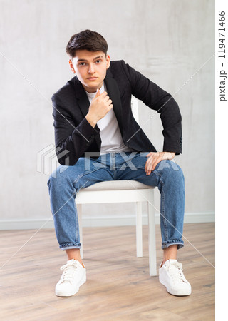 Charismatic young man sitting on chair in the middle of the room 119471466