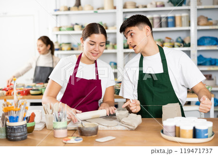 Joyous young man and woman sculpting handmade cups Joyous young man and woman sculpting handmade cups 119471737