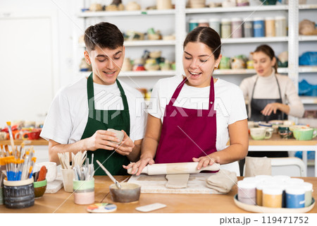 Joyous young man and woman sculpting handmade cups Joyous young man and woman sculpting handmade cups 119471752