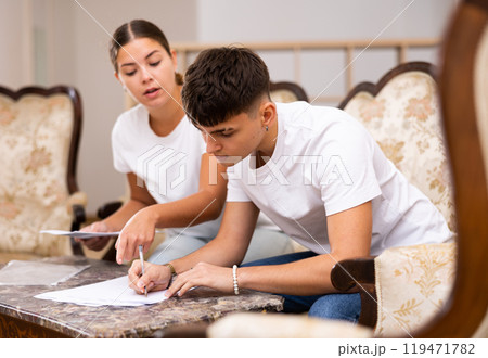 Young couple is studying the documents and signing them Young couple is studying the documents and signing them 119471782