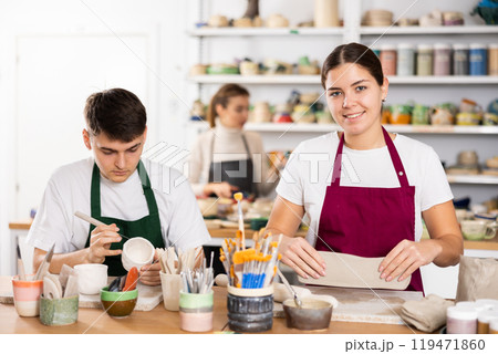 Joyous young man and woman sculpting handmade cups Joyous young man and woman sculpting handmade cups 119471860