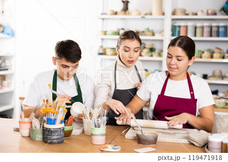 Young man and woman sculpting cups with master 119471918