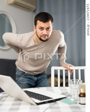 Young man suffering from low back pain at home 119471973