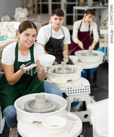 Young woman holding clay bawl at pottery wheel 119471990