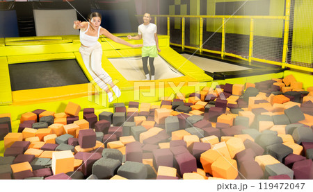 Happy athletes, man and girl, training to jump on trampolines at trampoline center 119472047