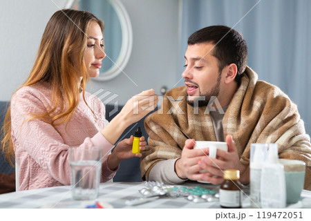 Man with viral disease sitting at home table with worried wife Man with viral disease sitting at home table with worried wife 119472051