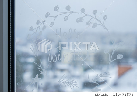 Sustainable responsible holiday decor. Hello winter text painted on window glass indoor at home. Christmas winter decoration. White pattern. Snow art tracery on season. Diy 119472875