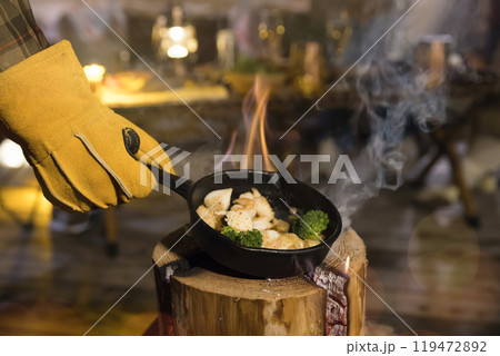 スウェーデントーチでアヒージョをする男性手元 119472892