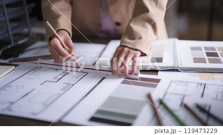 Female architect drawing building project and designing interior on blueprint with pencil and ruler 119473229