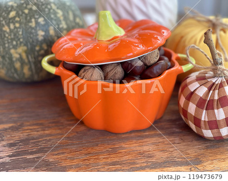Pot of nuts, chestnuts and pumpkins on wooden old table. Composition for Halloween holiday. Autumn and harvest. Pot of nuts, chestnuts and pumpkins on wooden old table. Composition for Halloween holiday. Autumn and harvest. 119473679