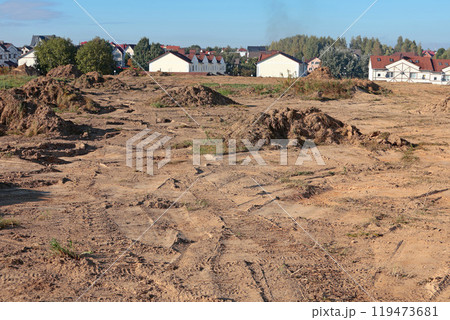 Leveling the ground for building new residential neighborhood. Heaps of land on construction site against background of built houses. Buildings and the performance of construction work.  119473681