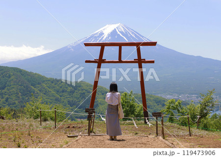 a girl pray in front of a traditional red Torii gate with the landscape of Mt. Fuji   a girl pray in front of a traditional red Torii gate with the landscape of Mt. Fuji   119473906