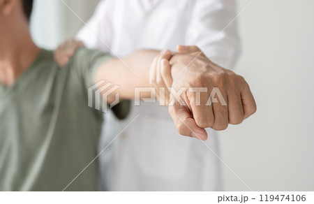 Female physiotherapists provide physical assistance to male patients with shoulder injuries massaging their shoulders for muscle recovery in the rehabilitation center. Physiotherapy concepts 119474106