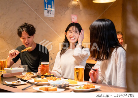 居酒屋でお酒を飲む若い男女 119474709