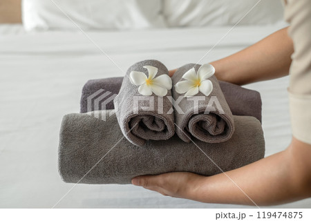 A hotel maid stacked towels on the bed and placed flowers on the towels in a hotel room 119474875