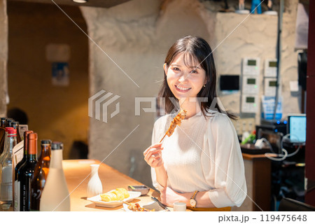 一人でカウンター席に座って焼き鳥を食べる女性 一人でカウンター席に座って焼き鳥を食べる女性 119475648