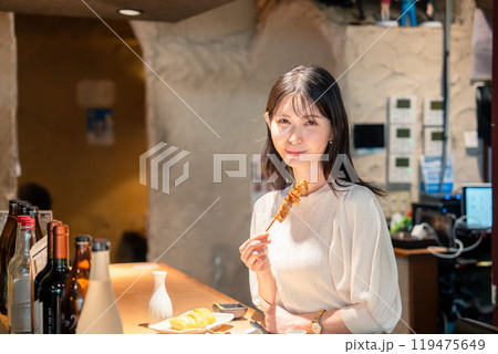一人でカウンター席に座って焼き鳥を食べる女性 一人でカウンター席に座って焼き鳥を食べる女性 119475649