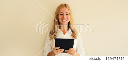 Happy smiling young woman employee with digital tablet computer or folder with documents in office Happy smiling young woman employee with digital tablet computer or folder with documents in office 119475813