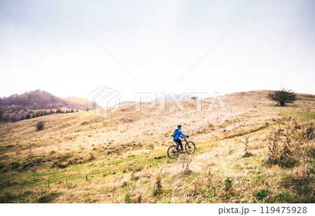 Cyclist far in the middle of beautiful nature during early autumn morning. Concept of healthy lifestyle. Cyclist far in the middle of beautiful nature during early autumn morning. Concept of healthy lifestyle. 119475928