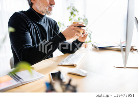 Homeoffice for handsome man. Man drinking coffee in the morning, working on computer from home. Telecommuting. Homeoffice for handsome man. Man drinking coffee in the morning, working on computer from home. Telecommuting. 119475951
