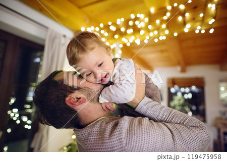 Little baby boy with dad in Christmas home. Father holding cute boy in the air, kissing him and playing with him. 119475958