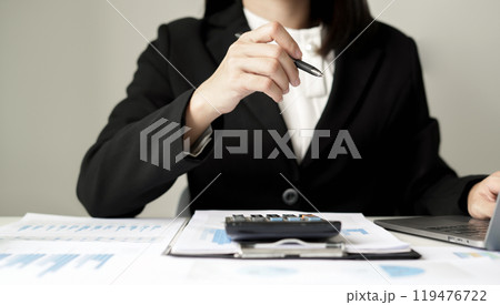 Asian businesswoman sit at their desks and calculate financial graphs showing results about their investments and plan successful business growth process Asian businesswoman sit at their desks and calculate financial graphs showing results about their investments and plan successful business growth process 119476722