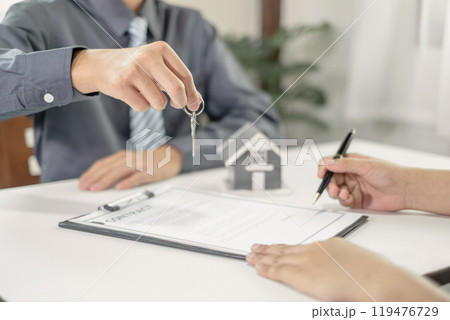 Real estate agent broker hand over the house key to the new owner after completing the signing according to the agreement renting a house and buy house insurance Home insurance concept 119476729