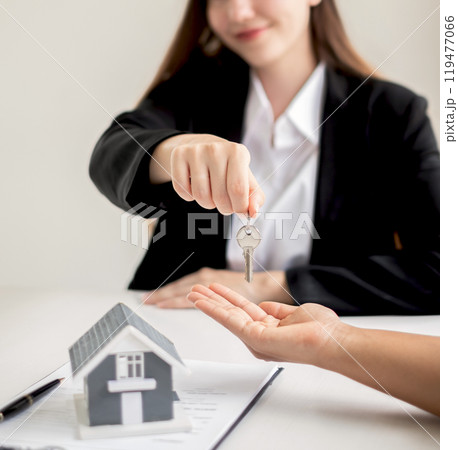 The real estate agent broker hand over the house key to the new owner after completing the signing according to agreement renting a house and buying house insurance officially completed 119477066