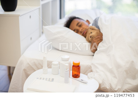 Young boy resting with stuffed animal and medication nearby Young boy resting with stuffed animal and medication nearby 119477453