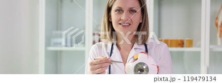 Positive woman points pen to realistic model of eyeball 119479134