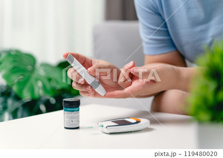 Asian woman using lancet on finger for checking blood sugar level by Glucose meter Asian woman using lancet on finger for checking blood sugar level by Glucose meter 119480020