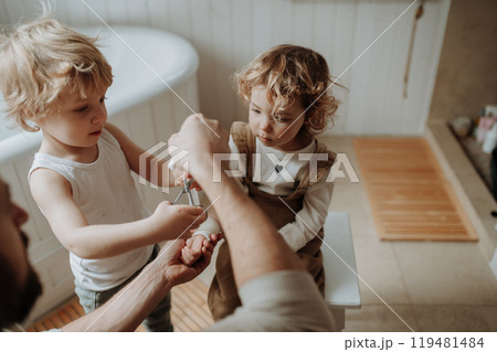 Father is bandaging his daughter's injured wrist in bathroom, concentrating while using a bandage. Father is bandaging his daughter's injured wrist in bathroom, concentrating while using a bandage. 119481484