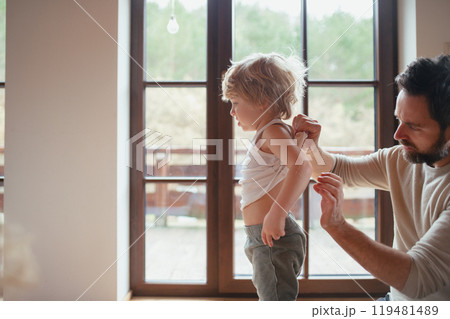 Father is checking his son's skin, looking for rashes or skin reactions. Father is checking his son's skin, looking for rashes or skin reactions. 119481489