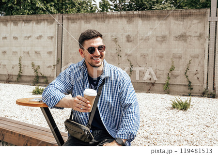 Cheerful man enjoying coffee at an outdoor cafe 119481513