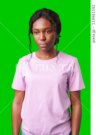 Young woman with an expression of contemplation poses against a bright green background Young woman with an expression of contemplation poses against a bright green background 119481592