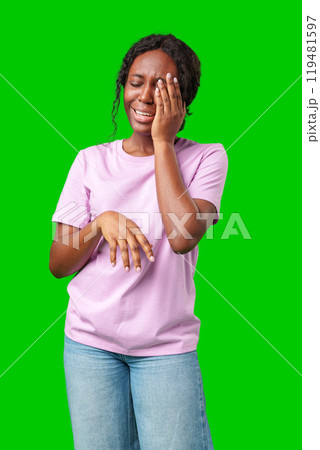 Woman expressing frustration while standing against a bright green background 119481597