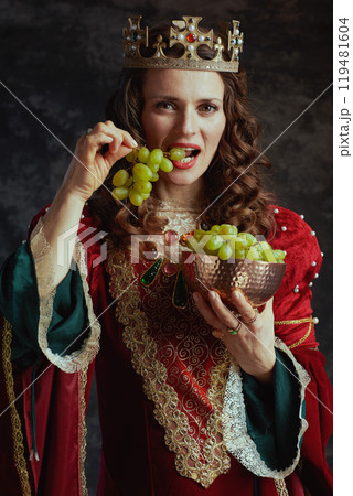 medieval queen in red dress with plate of grapes and crown medieval queen in red dress with plate of grapes and crown 119481604