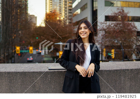 Smiling Canadian businesswoman standing outdoors in bustling downtown area. 119481925