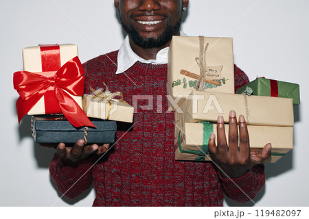 Smiling Man Holding Array of Colorful Wrapped Gifts Smiling Man Holding Array of Colorful Wrapped Gifts 119482097