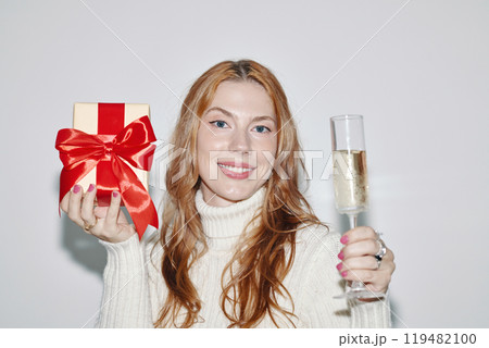 Smiling Woman Holding Gift and Champagne Glass 119482100