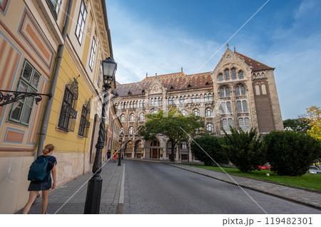 Budapest, Hungary. August 26, 2022. Perspective shot while walking along the streets of Pest. The colorful facades of the houses line the street. In the background the National Archives of Hungary. 119482301