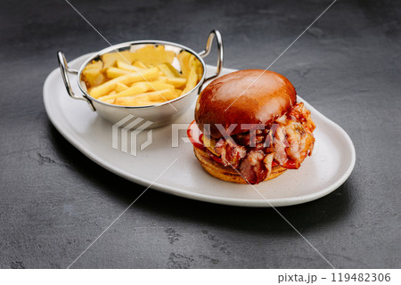 Juicy bacon cheeseburger with fries served on a stylish plate, perfect for a satisfying meal 119482306